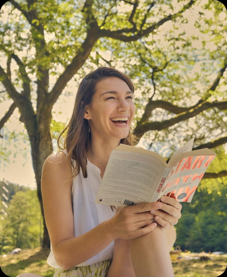 Simone Eiermann, founder of Nomads in the Wild, laughing while reading in a park